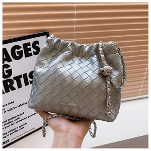 Detail of silver woven bucket bag featuring metal chain strap and spherical knot buckle