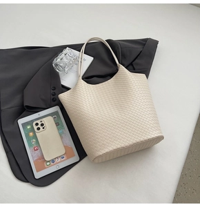 Makroaufnahme einer beigen gewebten Tragetasche mit kleiner Tasche und Büroartikeln