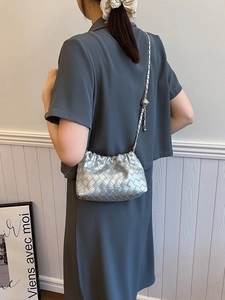 Chic silver woven crossbody bucket bag with chain strap shown on model back view