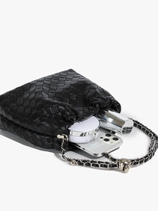 Black woven leather bucket bag with silver chain strap and skull detail in matte finish