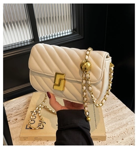 Detail of quilted flap bag with golden chain strap and hollow ball adjuster feature
