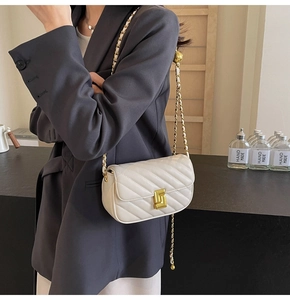 Close-up of beige quilted chain bag with gold rotary lock on a charcoal blazer