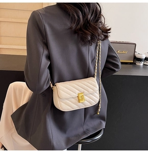 Detailed view of cream quilted chain bag with gold square lock on a fashion model