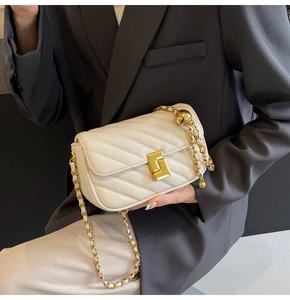 Detail view of white chevron quilted bag featuring gold metal lock and elegant chain strap