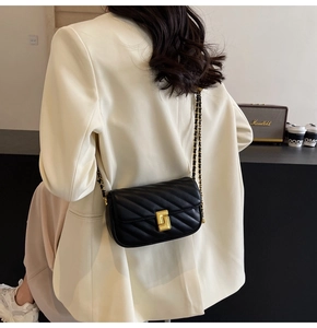 Detail of black quilted leather shoulder bag with gold chain strap and turn-lock