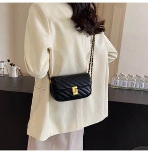 Detail of black quilted leather shoulder bag with gold chain strap and metal lock