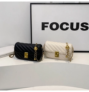 Close-up of quilted chain bag with gold metal square buckle and leather strap details