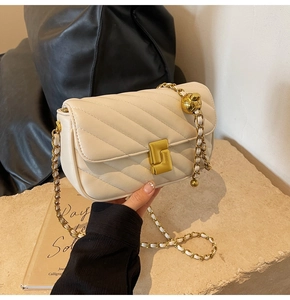 Detail of cream quilted bag featuring gold chain strap with adjustable gold ball charm