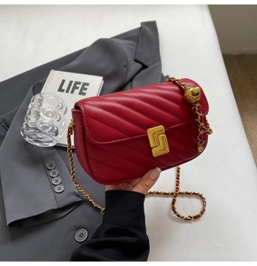 Close-up of red quilted crossbody bag with gold geometric lock and chain strap