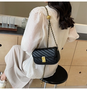 Detail of adjustable gold ball buckle on black quilted chain strap shoulder bag