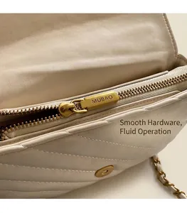 Close-up of beige quilted leather crossbody bag with polished gold zipper and chain strap