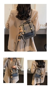 Detail of vintage grey crossbody bag with gold rivets and cute rabbit doll pendant