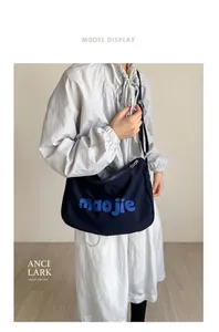 Detail view of navy blue canvas tote bag with 3D letters shown on a female model