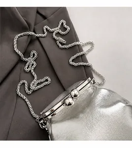 Detail of silver metallic mini bag with kiss-lock closure and woven chain strap