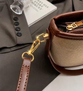 Close-up of premium gold-toned metal buckles and hardware on a leather canvas bucket bag