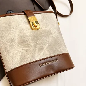 Close-up of retro bucket bag with gold metal lock and leather canvas stitching details