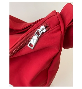 Close-up of a premium silver metal zipper on a vibrant red synthetic fabric shoulder bag