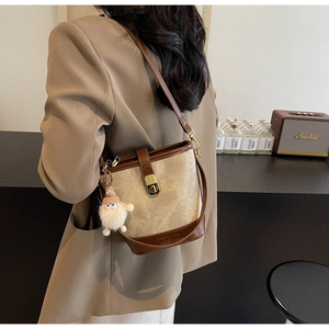 Détail du sac seau en toile rétro avec garniture en cuir et pendentif peluche
