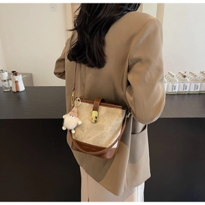Détail du sac seau en toile et cuir marron avec pendentif en peluche et boucle dorée