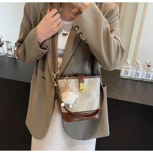 Détail du sac seau en toile avec bordure en similicuir marron et breloque pelucheuse