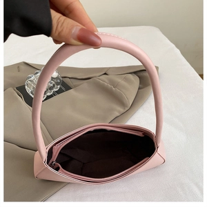 Detail of pink crescent underarm bag with zipper closure and brown lining