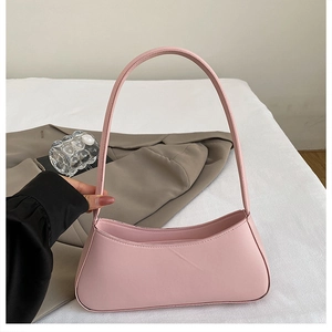 Detail of pink minimalist baguette bag showing matte faux leather texture and round handle