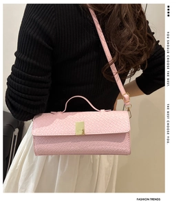 Pink woven leather shoulder bag with gold metal buckle shown in a lifestyle pose