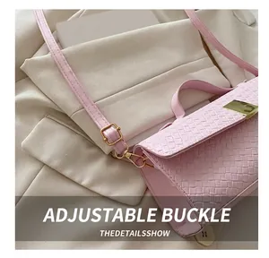 Close-up of pink woven handbag featuring a metallic adjustable buckle and shoulder strap