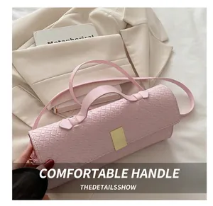 Close-up of pink woven cylindrical handbag with a golden clasp on a white suit
