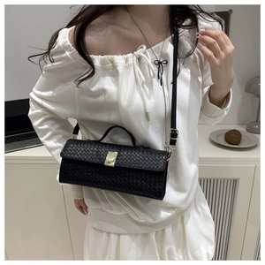 Detail of black woven leather texture and gold metal buckle on a shoulder bag