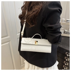 White woven leather handbag with gold buckle shown on shoulder of model in black suit