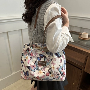 Canvas tote bag with butterfly prints, metal chain and leather strap in a lifestyle setting