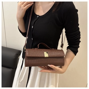 Close-up of brown woven leather texture and golden metal buckle on crossbody bag