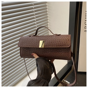 Close-up of brown woven leather texture and elegant gold buckle on a stylish bag