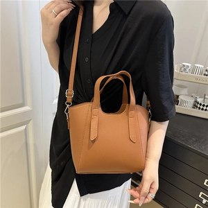 Brown lychee leather tote bag with gold hardware and adjustable strap worn by model