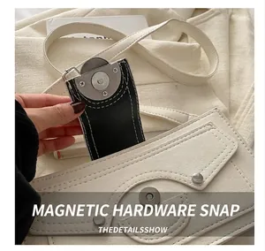 Close-up of industrial style metal buckle and lychee texture on off-white leather bag