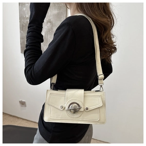 Détail du sac à bandoulière rectangle beige avec boucle métallique et texture en cuir