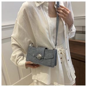 Detailed view of gray fabric crossbody bag featuring a silver round buckle and stud accents