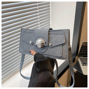 Detail of blue-grey suede shoulder bag featuring a silver planet-shaped metal buckle