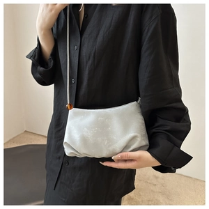 Gros plan du sac nuage argenté plissé avec perle ambrée sur la bandoulière de mode