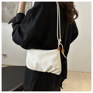 Détail du sac nuage plissé blanc avec bandoulière en corde et perles ambrées