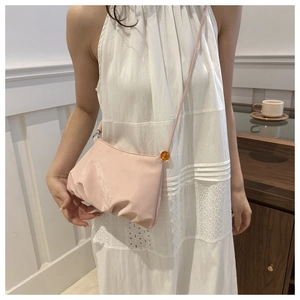 Detalle de bolso nube plisado rosa claro con cuenta de ámbar y correa de hombro fina