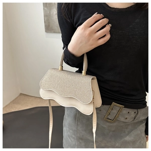 Detail of champagne gold glitter evening bag with wavy flap and slim shoulder strap