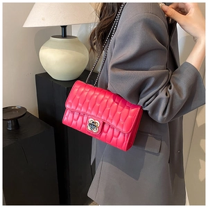 Close-up of quilted magenta crossbody bag with gold flower clasp and chain strap