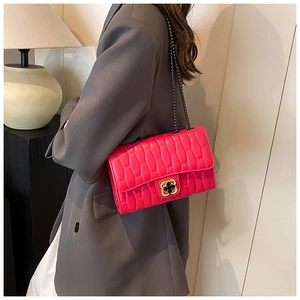 Detail of fuchsia quilted chain bag with gold floral clasp on a grey blazer