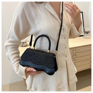 Dettaglio della mini borsa nera con trama glitterata e base con bordo ondulato
