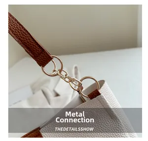 Macro detail of gold metal hardware and litchi texture leather on tote bag