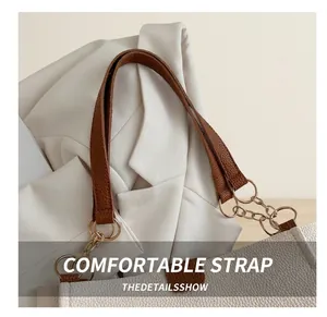 Detail of brown litchi leather strap and gold chain on a stylish women tote bag