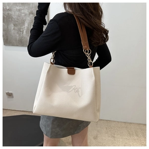 Close-up of white lychee leather tote bag with brown straps and golden chain accents