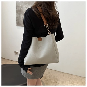 Detail of grey lychee leather tote with brown strap and gold metal chain hardware